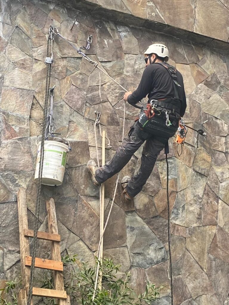 Técnico en rapel con sistema de cuerdas en muro de piedra